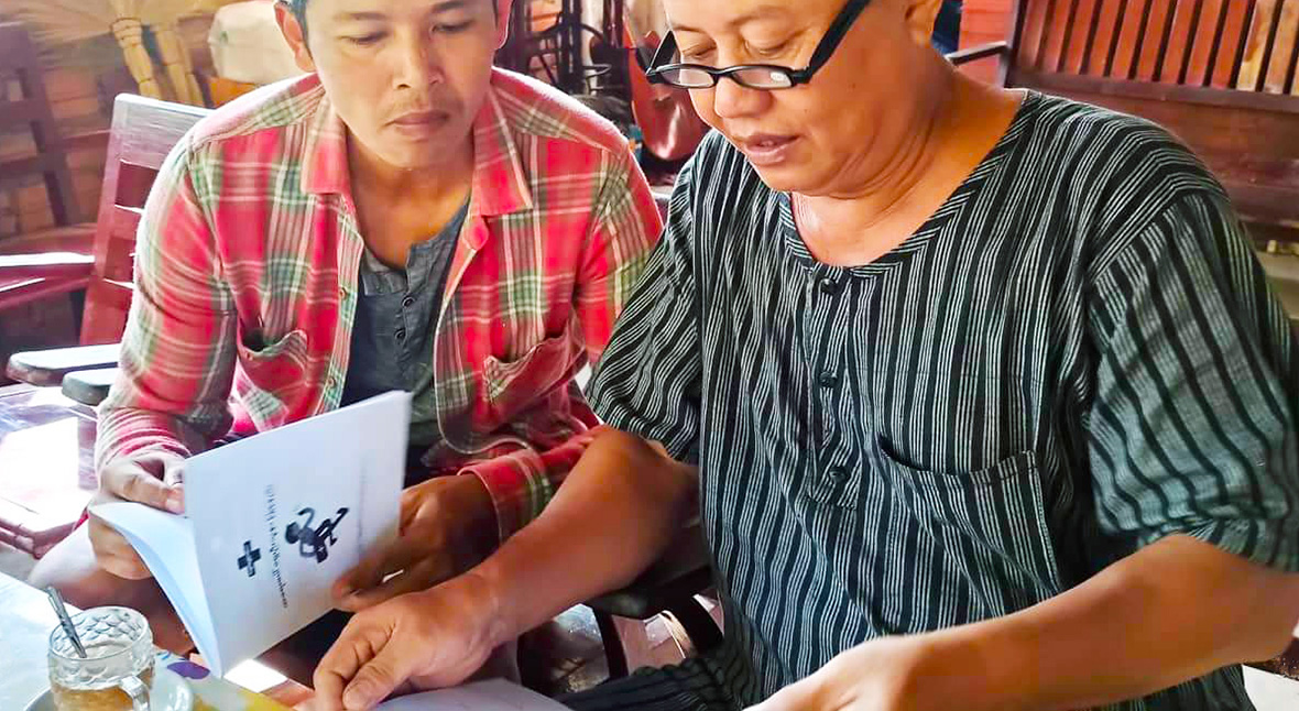 Two people in Myanmar looking at first aid training materials